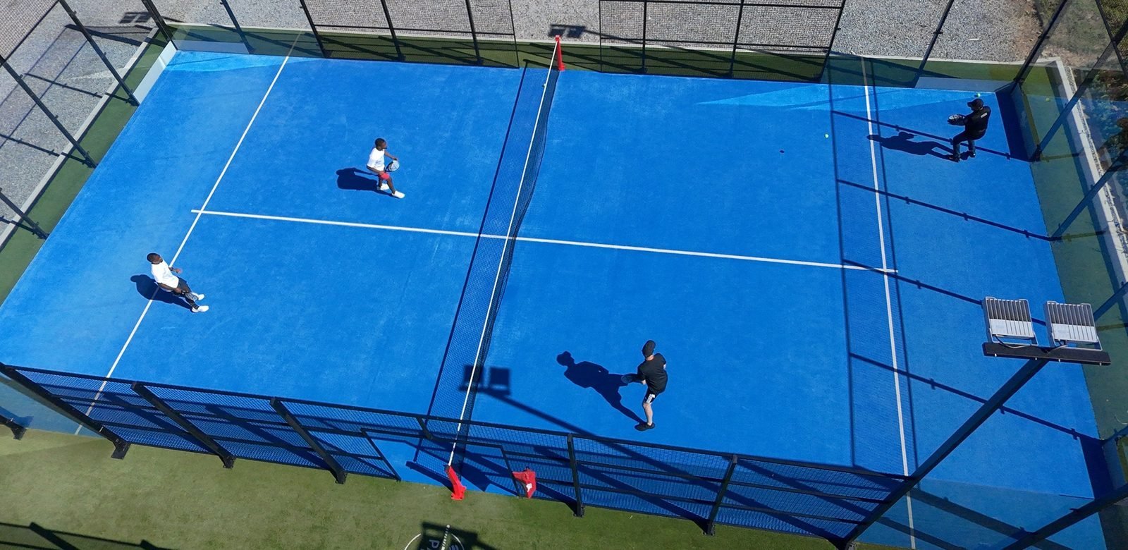 A padel court from above, with four players mid-rally